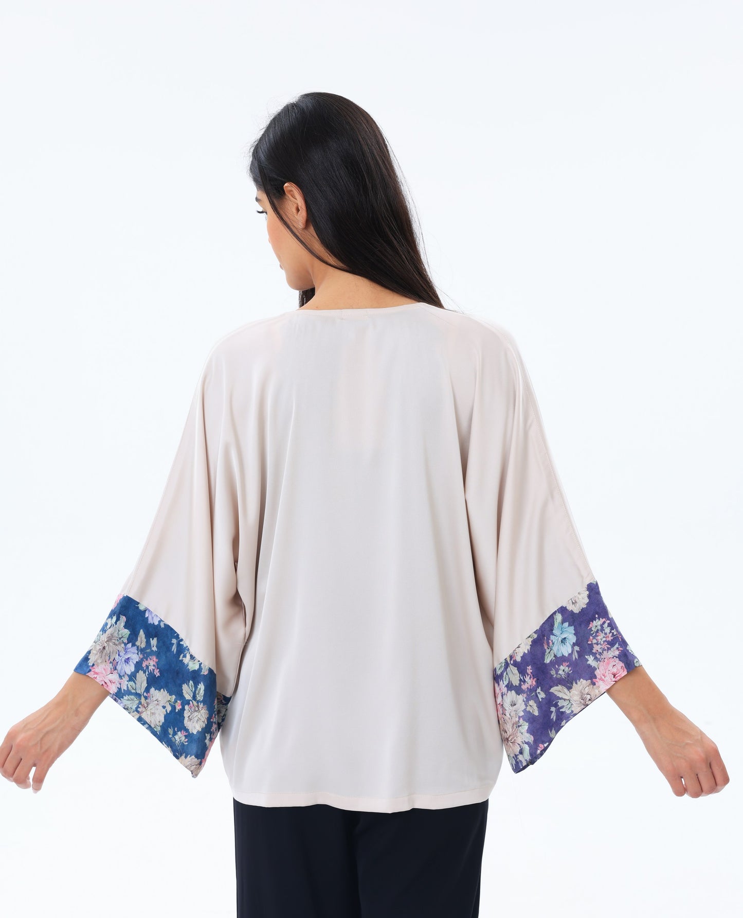 Woman wearing a beige top kimono with floral cuffs on a white background