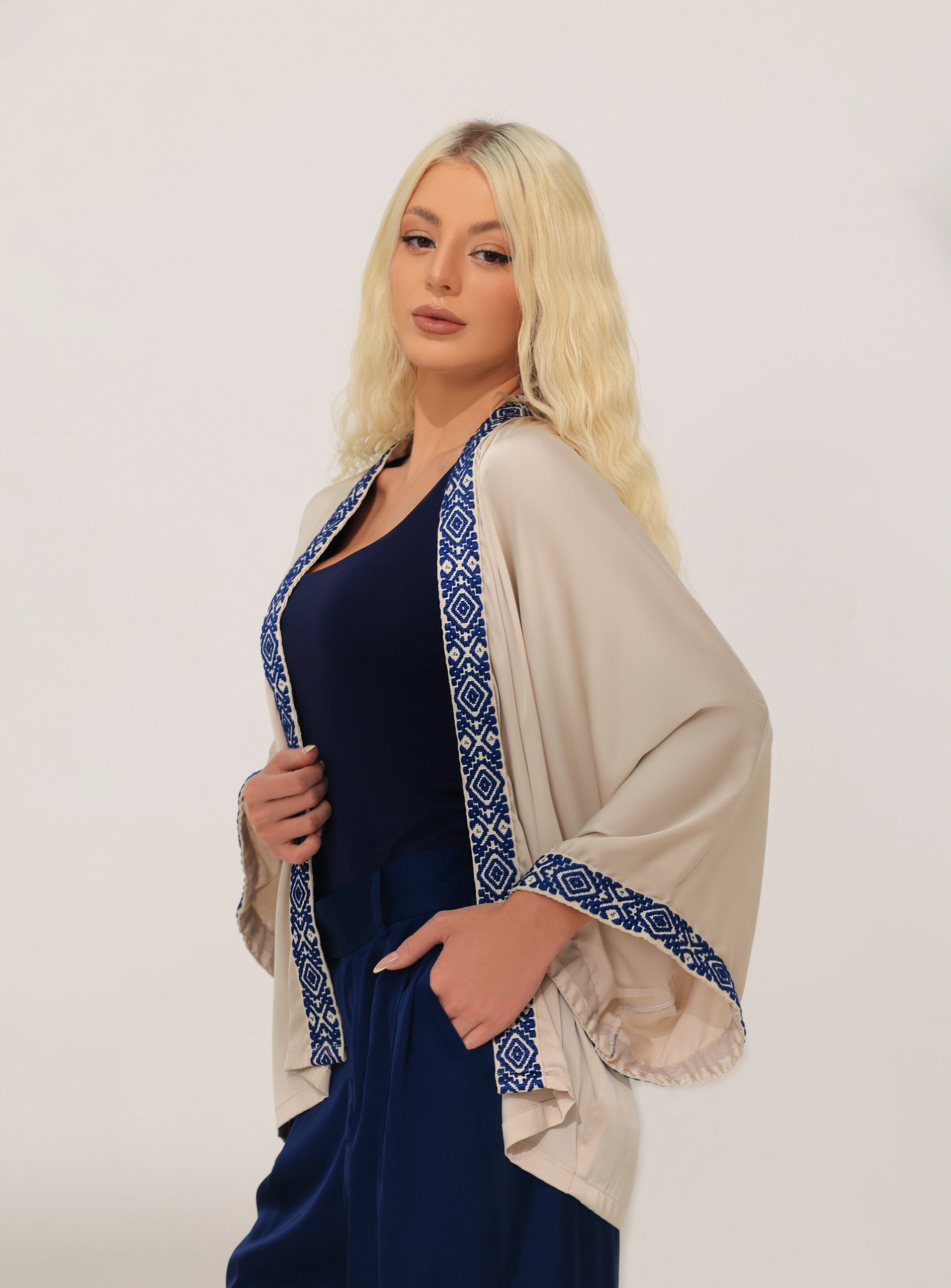 Woman wearing a beige kimono featuring blue Greek patterns on a white background