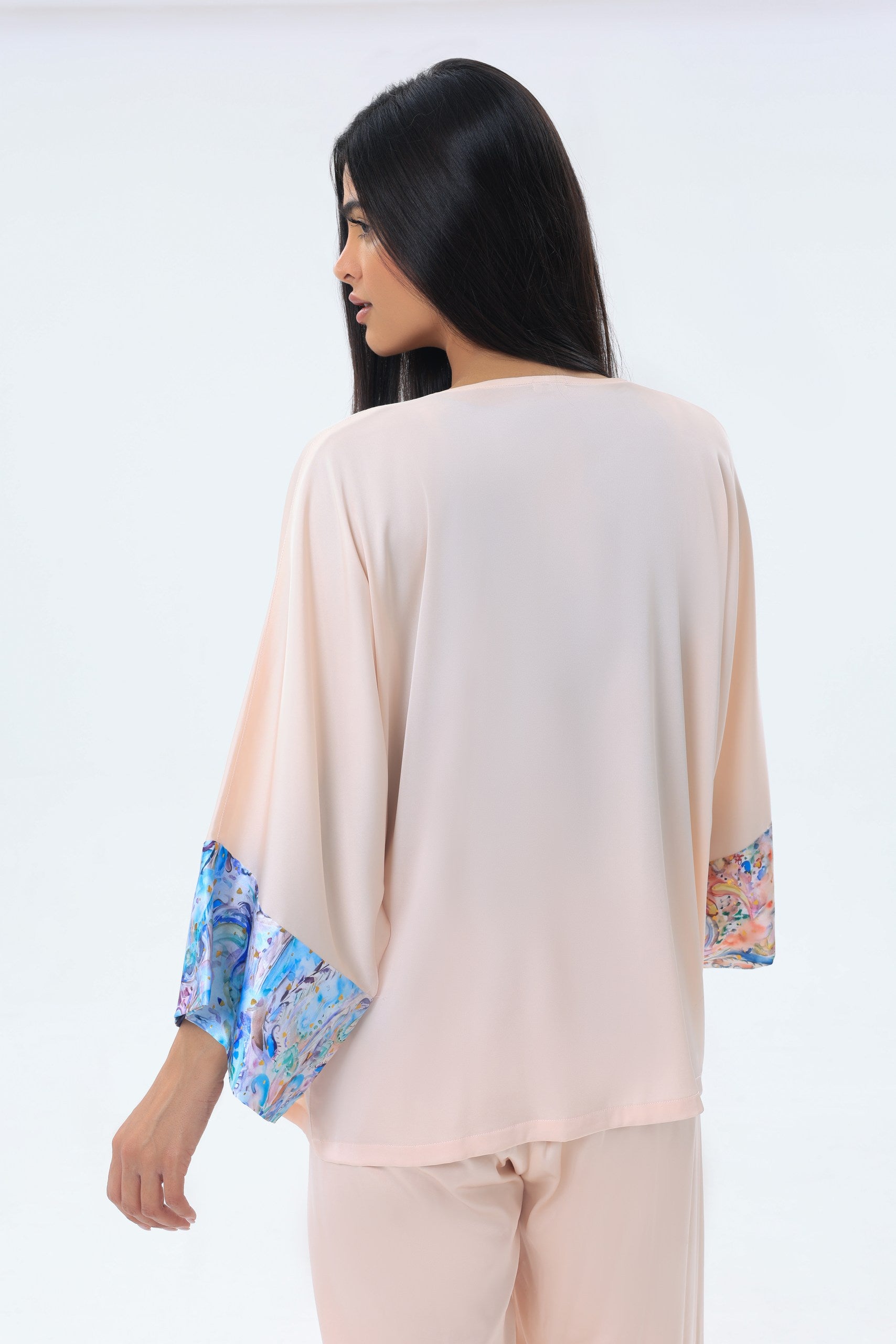 Woman wearing a peach modest kimono with floral cuffs on a white background