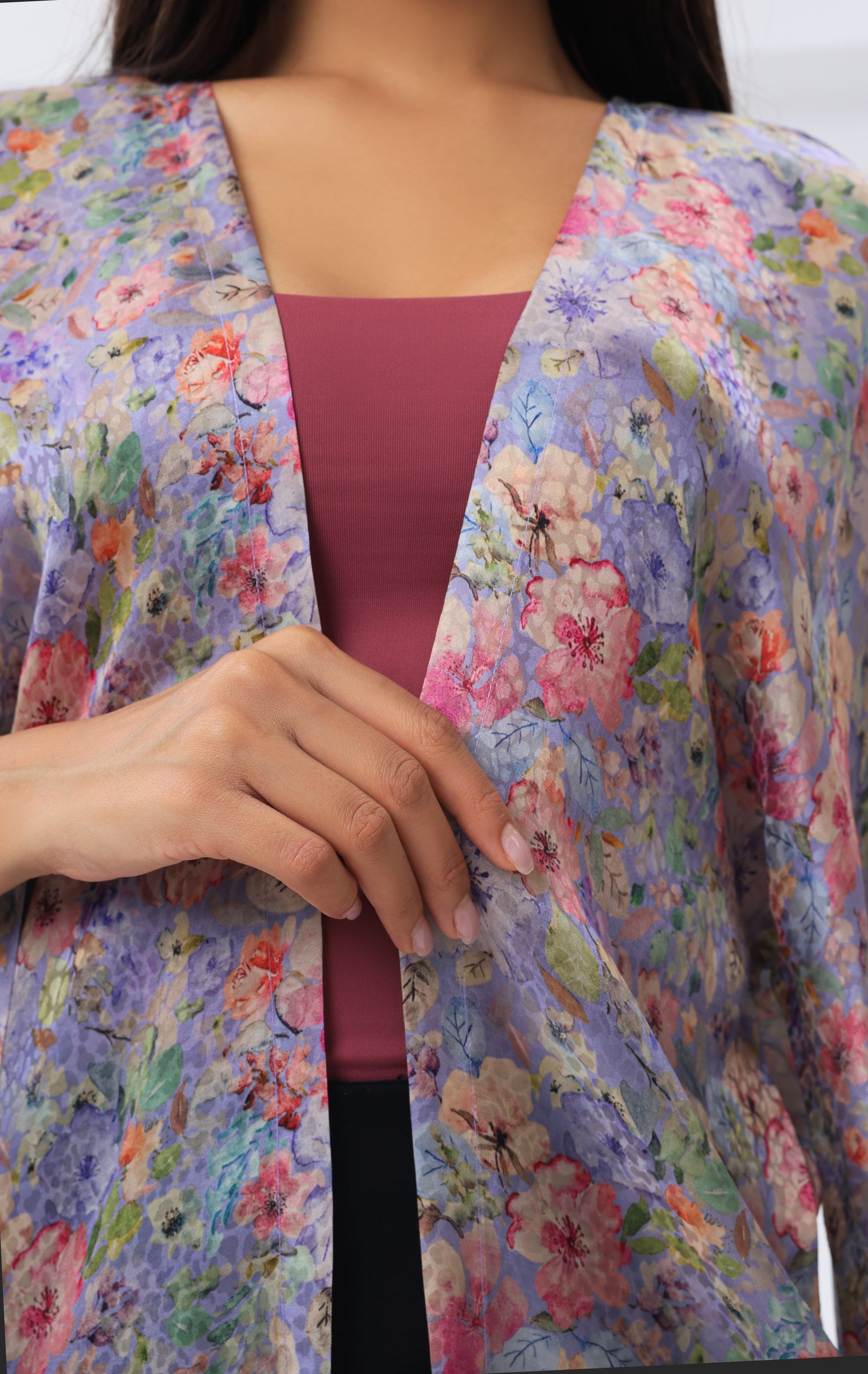Person wearing a floral modest kimono over a pink top with a blurred background