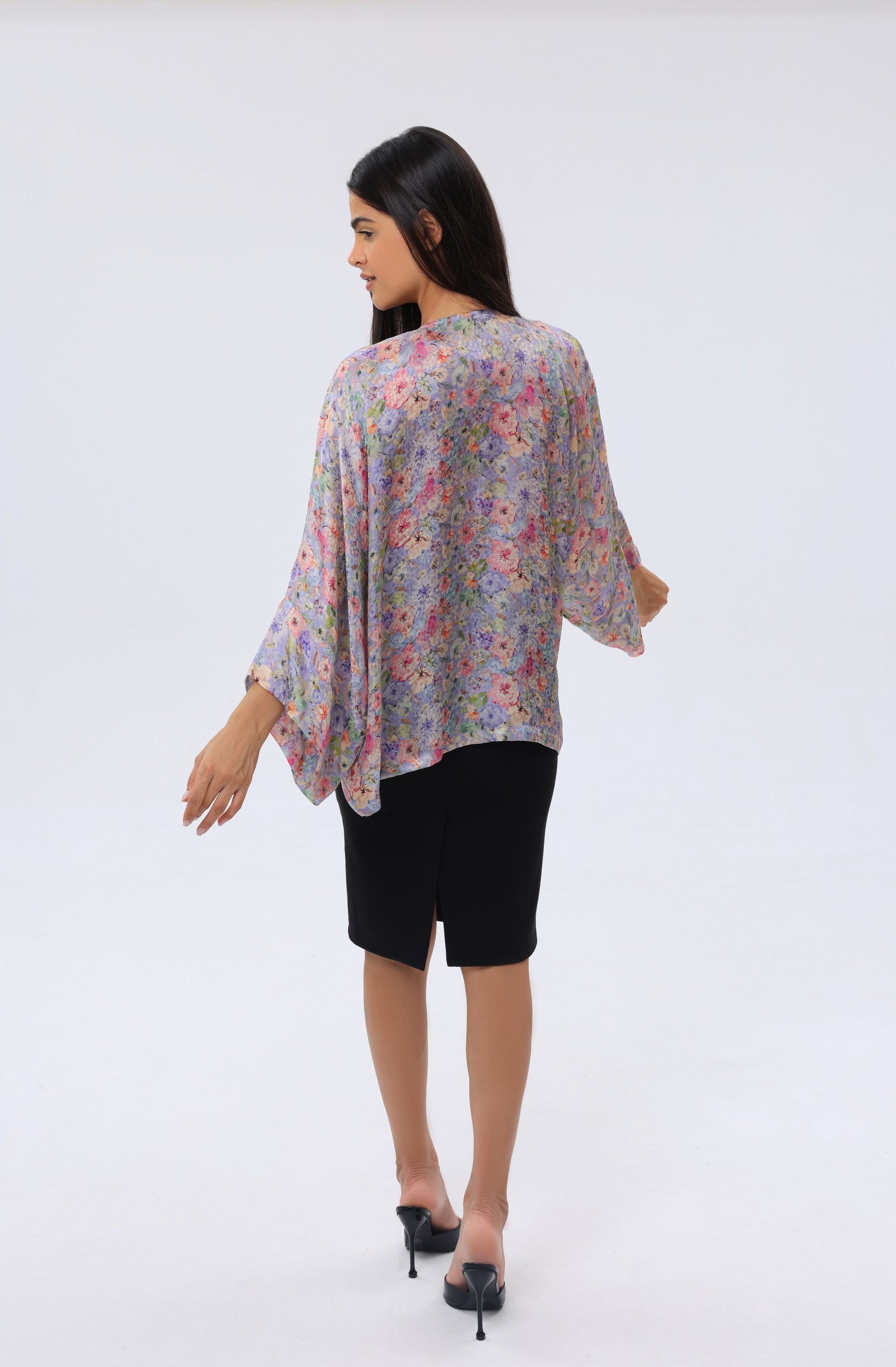 Woman wearing a modest, floral kimono cover up and black skirt on a white background