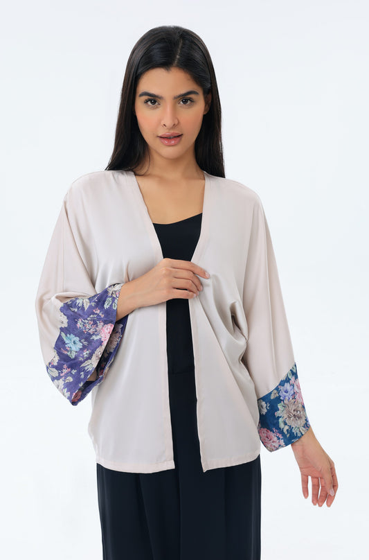 Woman wearing a beige kimono with floral cuffs on a white background